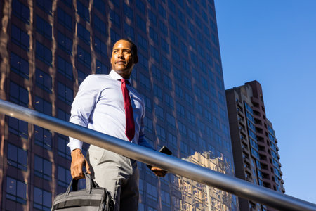 Handsome male african american business man CEO in a stylish corporate elegant suit in a business center outdoors - Black male commuter going to work, city and financial district in the backgroundの写真素材