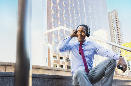 Handsome male african american business man CEO in a stylish corporate elegant suit in a business center outdoors - Black male commuter going to work, city and financial district in the backgroundの写真素材