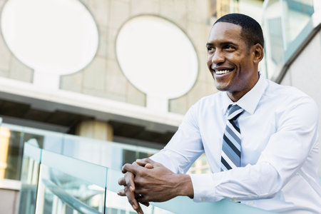 Handsome male african american business man CEO in a stylish corporate elegant suit in a business center outdoors - Black male commuter going to work, city and financial district in the backgroundの写真素材