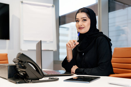 Middle-eastern businesswoman wearing traditional arab abaya working in the office in Dubai - Adult...