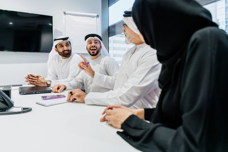 Group of middle-eastern corporate business people wearing traditional emirati clothes meeting in the office in Dubai - Business team working and brainstorming in the UAEの写真素材