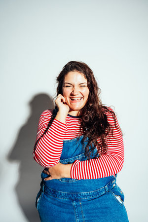 Plus size woman model posing in studio and having fun. Shots taken on white background and direct hard lightの写真素材