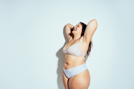 Plus size woman posing in studio in lingerie. Model on white background. Hard light studio shotの写真素材
