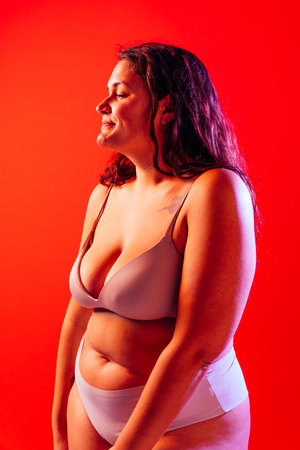 Plus size woman posing in studio in lingerie. Model on colored background. Hard light studio shotの写真素材