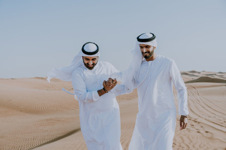 Two middle-eastern men wearing traditional emirati arab kandura bonding in the desert - Arabian...