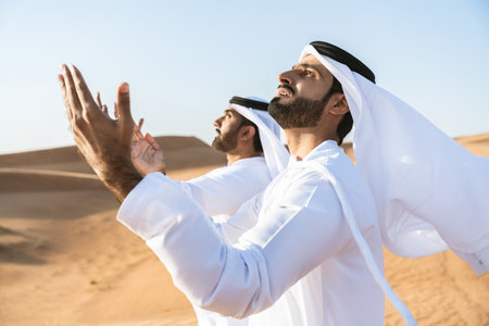 Two middle-eastern men wearing traditional emirati arab kandura bonding in the desert - Arabian...