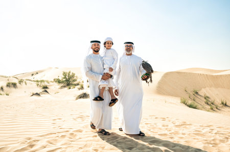 Three generation family making a safari in the desert of Dubai. Grandfather, son and grandson spending time together in the nature and training their falcon bird.の写真素材