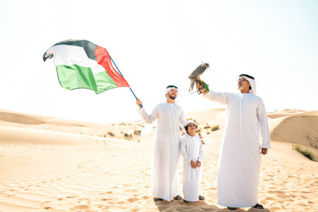 Three generation family making a safari in the desert of Dubai. Grandfather, son and grandson spending time together in the nature and training their falcon bird.の写真素材