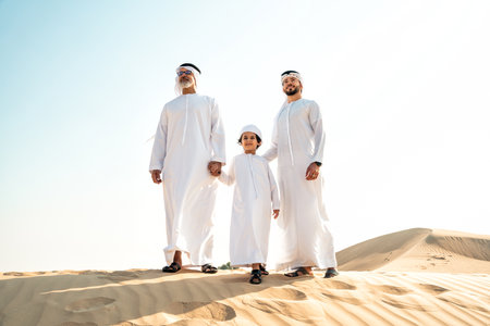 Three generation family making a safari in the desert of Dubai wearing white kandura outfit....
