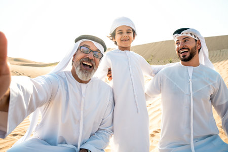 Three generation family making a safari in the desert of Dubai wearing white kandura outfit....