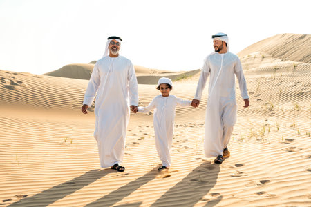 Three generation family making a safari in the desert of Dubai wearing white kandura outfit. Grandfather, son and grandson spending time together in the nature.の写真素材