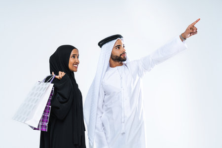Beautiful arab middle-eastern happy couple of lovers wearing traditional abaya and kandora in studio - Arabic muslim adult people bonding and having fun in Dubai, United Arab Emiratesの写真素材