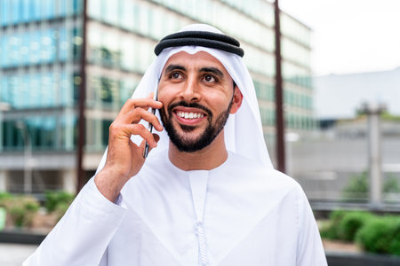 Arab middle-eastern man wearing emirati kandora traditional clothing in the city - Arabian muslim businessman strolling in urban business centre.の写真素材