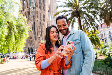 Multiracial beautiful happy couple of lovers dating at Sagrada Familia, Barcelona - Multiethnic tourists traveling in Europe and visiting a city in Spain, concepts about tourism and people lifestyleの写真素材