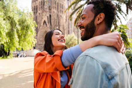 Multiracial beautiful happy couple of lovers dating at Sagrada Familia, Barcelona - Multiethnic tourists traveling in Europe and visiting a city in Spain, concepts about tourism and people lifestyleの写真素材