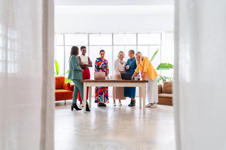 Group of beautiful confident businesswomen meeting in the office - Multiethinc female creative team brainstorming at work - Diverse colleagues working together in workshop in a co-working spaceの写真素材