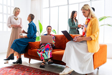 Group of beautiful confident businesswomen meeting in the office - Multiethinc female creative team brainstorming at work - Diverse colleagues working together in workshop in a co-working spaceの写真素材