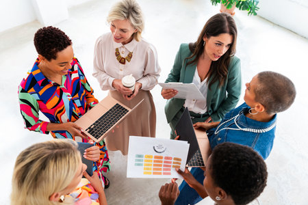 Group of beautiful confident businesswomen meeting in the office - Multiethinc female creative team brainstorming at work - Diverse colleagues working together in workshop in a co-working spaceの写真素材