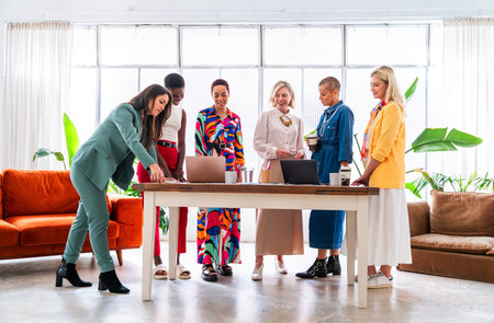 Group of beautiful confident businesswomen meeting in the office - Multiethinc female creative team brainstorming at work - Diverse colleagues working together in workshop in a co-working spaceの写真素材