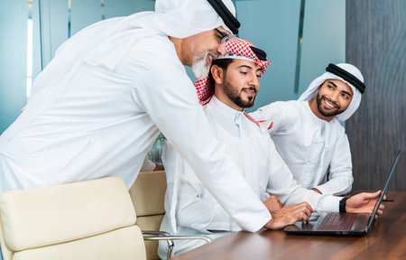 Group of corporate arab businessmen meeting in the office - Middle-eastern businesspeople wearing emirati kandora working in a meeting room, Dubaiの写真素材