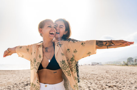 Beautiful multiethnic lesbian couple of lovers dating outdoors - LGBT people bonding and spending time together, concepts about LGBTQ community, diversity, love and lifestyleの写真素材