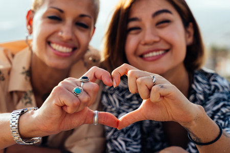 Beautiful multiethnic lesbian couple of lovers dating outdoors - LGBT people bonding and spending time together, concepts about LGBTQ community, diversity, love and lifestyleの写真素材