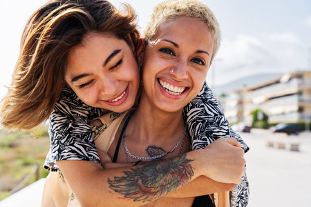 Beautiful multiethnic lesbian couple of lovers dating outdoors - LGBT people bonding and spending time together, concepts about LGBTQ community, diversity, love and lifestyleの写真素材