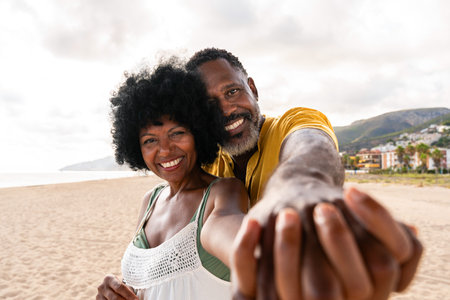 Beautiful mature black couple of lovers dating at the seaside - Married african middle-aged couple bonding and having fun outdoors, concepts about relationship, lifestyle and quality of lifeの写真素材