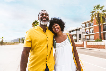 Beautiful mature black couple of lovers dating at the seaside - Married african middle-aged couple bonding and having fun outdoors, concepts about relationship, lifestyle and quality of lifeの写真素材
