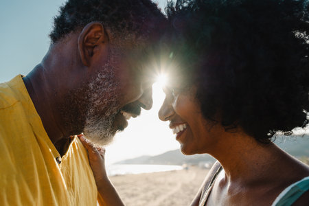 Beautiful mature black couple of lovers dating at the seaside - Married african middle-aged couple bonding and having fun outdoors, concepts about relationship, lifestyle and quality of lifeの写真素材