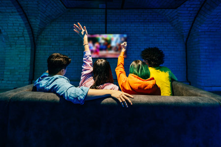 Multiethnic group of young friends playing videogames at home sitting on the sofa - Videogamers having fun playing e-sports at computer videogame consoleの写真素材
