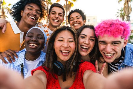 Multiethnic group of young happy friends hanging out in the city - Multiracial group of students meeting and having fun outdoors, concepts about youth, teenage, diversity and lifestyleの写真素材