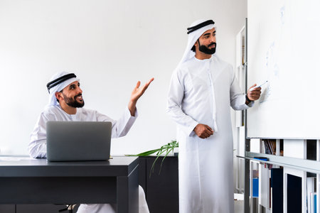 Arab men wearing traditional emirate clothing working in the office - Middle eastern businessmen brainstorming at workの写真素材