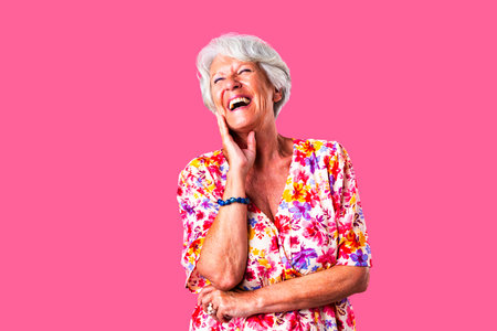 Beautiful senior woman with gray hair wearing colorful stylish clothing portrait in studio - Cheerful old grandmother with fashionable style laughingの写真素材