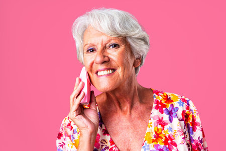 Beautiful senior woman with gray hair wearing colorful stylish clothing portrait in studio - Cheerful old grandmother with fashionable style doing a beauty skin care treatmentの写真素材