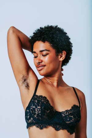 Beautiful black afro woman wearing lingerie posing for body positive concepts -Pretty female young adult not shaved on armpit posing for body acceptance, diversity, self-esteemの写真素材