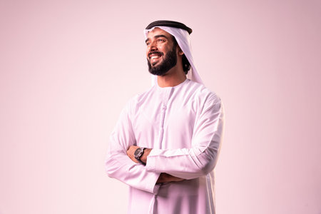 Arab businessman wearing emirates kandura portrait in studio in Dubai - Handsome middle eastern male adult posing on cut-out background - Muslim bearded man with traditional emirates clothingの写真素材