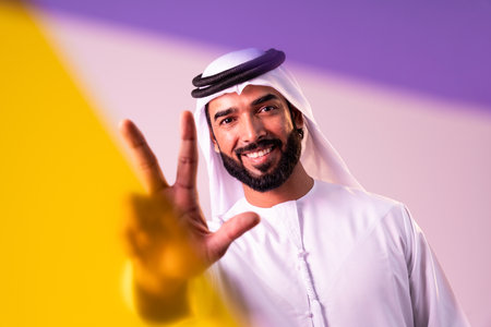 Arab businessman wearing emirates kandura portrait in studio in Dubai - Handsome middle eastern male adult posing on cut-out background - Muslim bearded man with traditional emirates clothingの写真素材