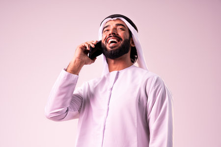 Arab businessman wearing emirates kandura portrait in studio in Dubai - Handsome middle eastern male adult posing on cut-out background - Muslim bearded man with traditional emirates clothingの写真素材