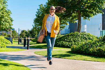 Beautiful senior businesswoman wearing business casual attire strolling in the city business...