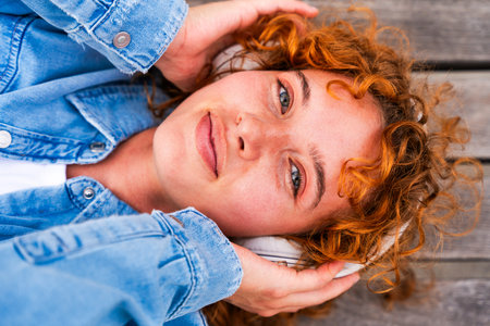 Portrait of cheerful and beautiful young girl with red hair strolling outdoors - Pretty female teen student with unique face and colorful attireの写真素材