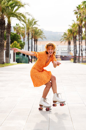 Beautiful red haired young woman with rollerskates having fun outdoors - Pretty female teenager girl with unique style riding on roller skates in the cityの写真素材