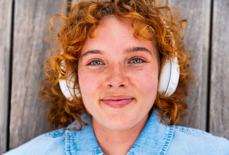 Portrait of cheerful and beautiful young girl with red hair strolling outdoors - Pretty female teen student with unique face and colorful attireの写真素材