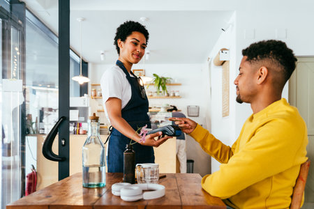 Bakery, happy portrait of black woman in cafe ready for serving pastry, coffee and baked foods. Restaurant, coffee shop and confident waiter barista by counter for service, help and welcomeの写真素材