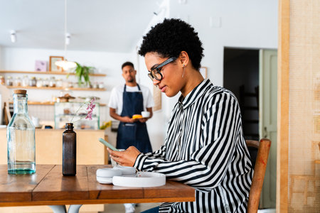 Bakery, happy portrait of hispanic black man in cafe ready for serving pastry, coffee and baked foods. Restaurant, coffee shop and confident waiter barista by counter for service, help and welcomeの写真素材