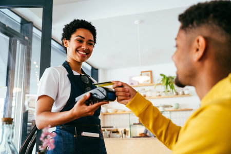 Bakery, happy portrait of black woman in cafe ready for serving pastry, coffee and baked foods. Restaurant, coffee shop and confident waiter barista by counter for service, help and welcomeの写真素材