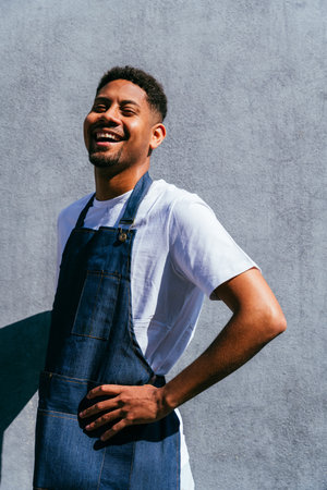 Bakery, happy portrait of hispanic black man in cafe ready for serving pastry, coffee and baked foods. Restaurant, coffee shop and confident waiter barista by counter for service, help and welcomeの写真素材