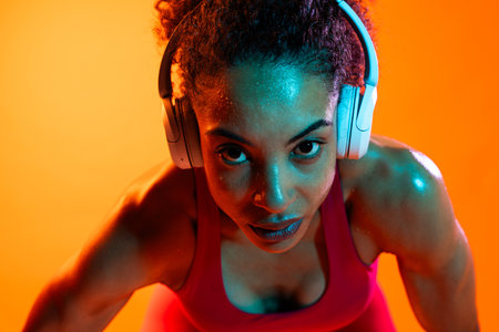 Sportive black hispanic woman wearing sportswear training in fitness studio, colorful dramatic lighting - African-american female athlete doing sport workoutの写真素材