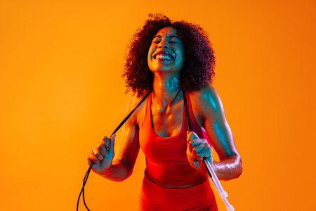 Sportive black hispanic woman wearing sportswear training in fitness studio, colorful dramatic lighting - African-american female athlete doing sport workoutの写真素材