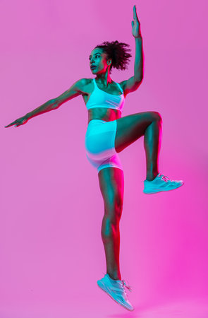 Sportive black hispanic woman wearing sportswear training in fitness studio, colorful dramatic lighting - African-american female athlete doing sport workoutの写真素材